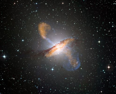 Colour composite image of Centaurus A, revealing the lobes and jets emanating from the active galaxy’s central black hole. This is a composite of images obtained with three instruments, operating at very different wavelengths. The 870-micron submillimetre data, from LABOCA on APEX, are shown in orange. X-ray data from the Chandra X-ray Observatory are shown in blue. Visible light data from the Wide Field Imager (WFI) on the MPG/ESO 2.2 m telescope located at La Silla, Chile, show the stars and the galaxy’s characteristic dust lane in close to "true colour".